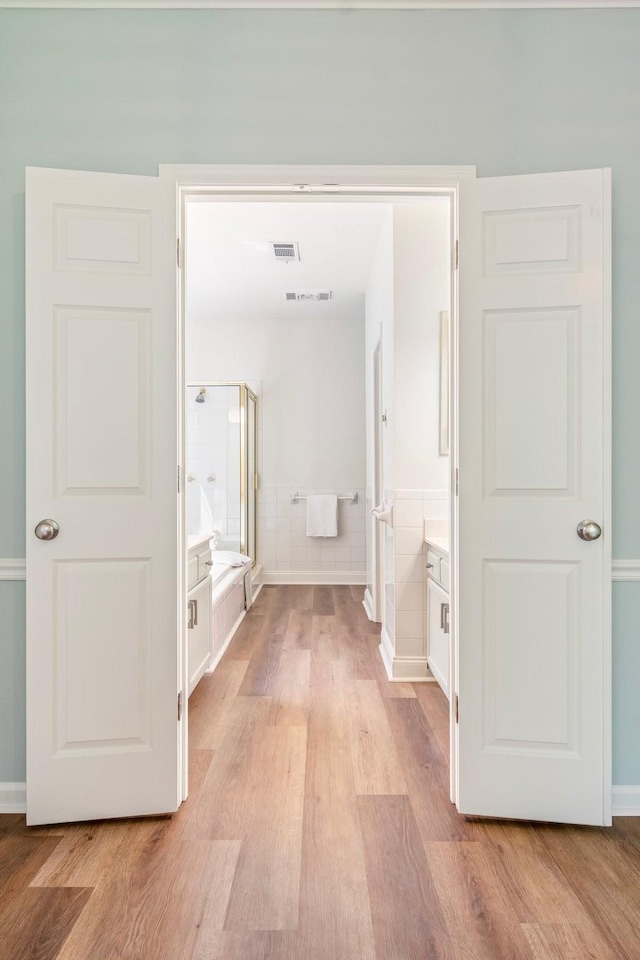 corridor featuring tile walls and light wood-type flooring