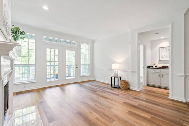 unfurnished living room featuring light wood-type flooring and crown molding