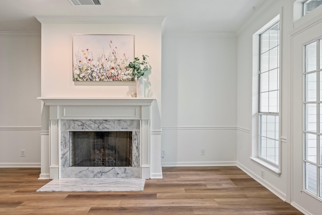 unfurnished living room with a premium fireplace, ornamental molding, and wood-type flooring