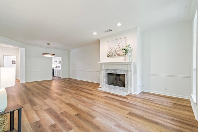 unfurnished living room featuring a fireplace, ornamental molding, and light hardwood / wood-style flooring