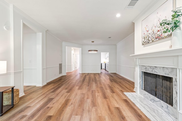 unfurnished living room featuring a premium fireplace, light hardwood / wood-style floors, and crown molding