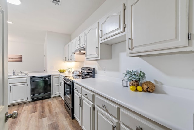 kitchen featuring sink, white cabinetry, light wood-type flooring, and black appliances