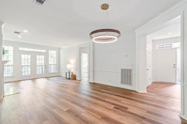 unfurnished living room with hardwood / wood-style flooring and crown molding