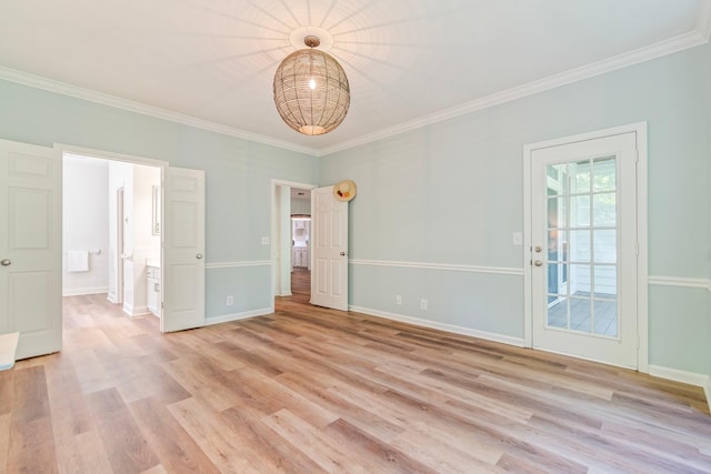 spare room featuring light wood-type flooring and crown molding