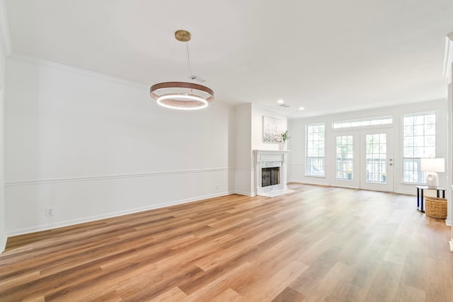 unfurnished living room featuring a premium fireplace, light wood-type flooring, and crown molding