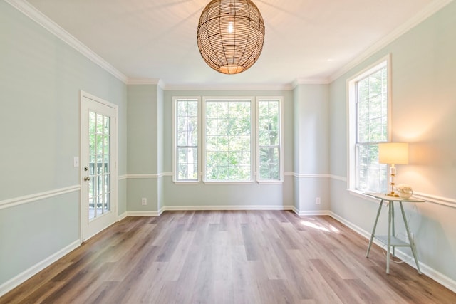 unfurnished room featuring hardwood / wood-style floors, ornamental molding, and a healthy amount of sunlight