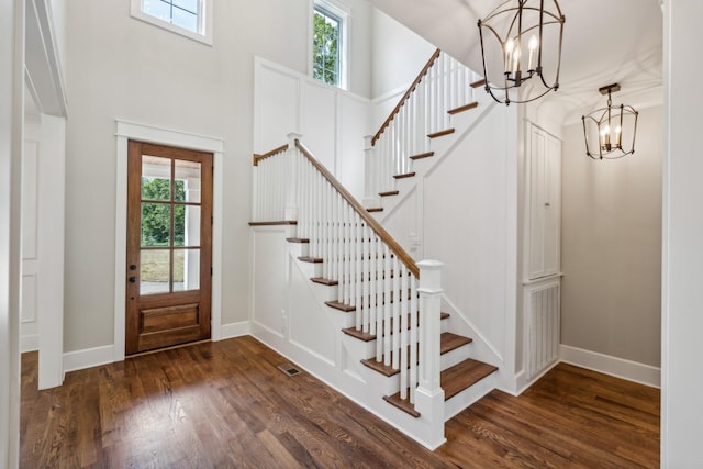 foyer entrance featuring a towering ceiling, a notable chandelier, and dark hardwood / wood-style flooring