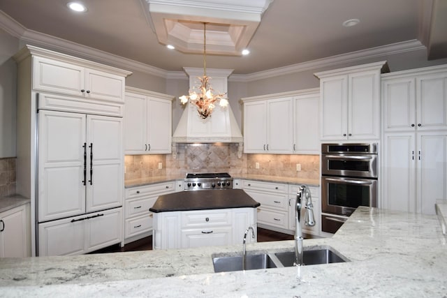 kitchen with dark stone countertops, crown molding, pendant lighting, stainless steel double oven, and white cabinets