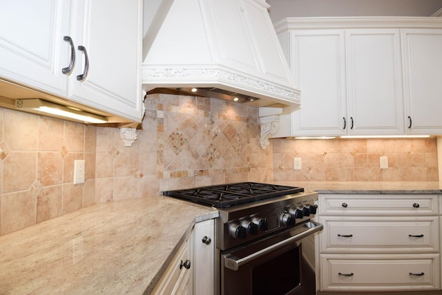 kitchen featuring white cabinetry, custom range hood, tasteful backsplash, light stone countertops, and stainless steel range