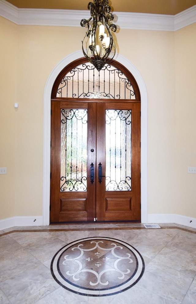 entryway featuring french doors, an inviting chandelier, and crown molding