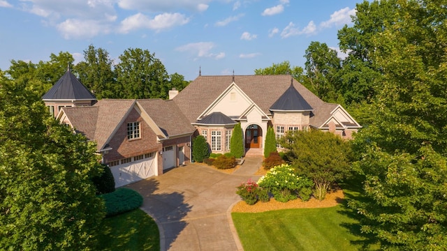 view of front of home featuring a standing seam roof, an attached garage, a chimney, concrete driveway, and metal roof