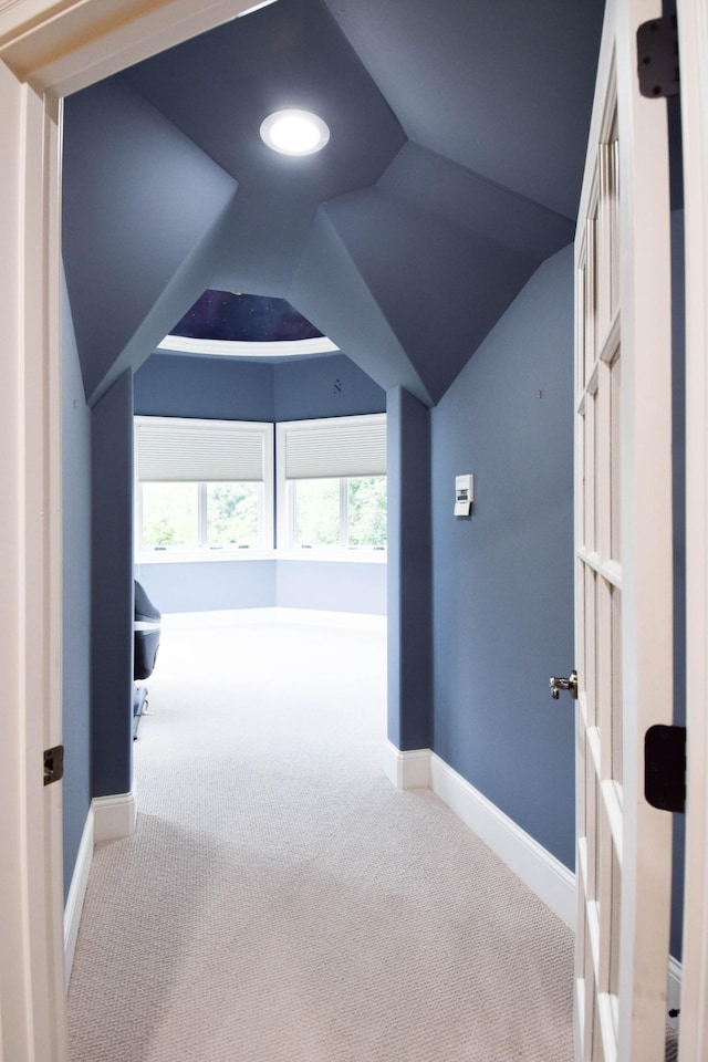 hall with carpet floors, vaulted ceiling, and a healthy amount of sunlight