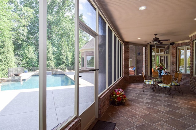 unfurnished sunroom featuring ceiling fan and a wealth of natural light