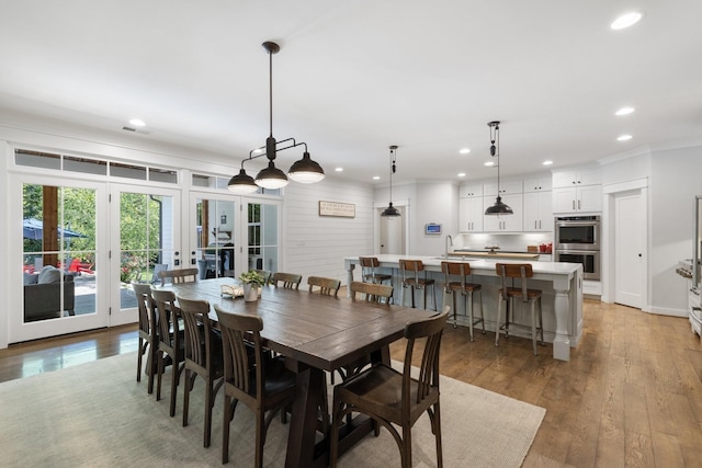 dining room with ornamental molding, french doors, light hardwood / wood-style floors, and sink