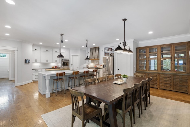 dining area with sink, light hardwood / wood-style flooring, and ornamental molding