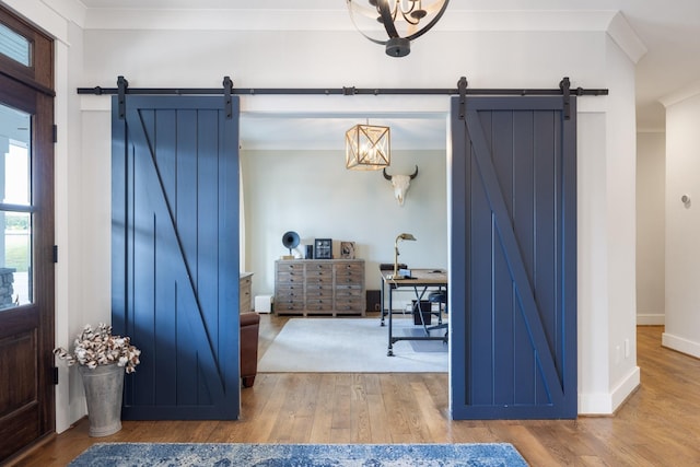 entrance foyer with wood-type flooring, ornamental molding, and a barn door