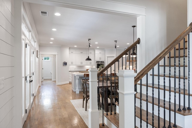 stairway featuring a healthy amount of sunlight, hardwood / wood-style floors, and ornamental molding