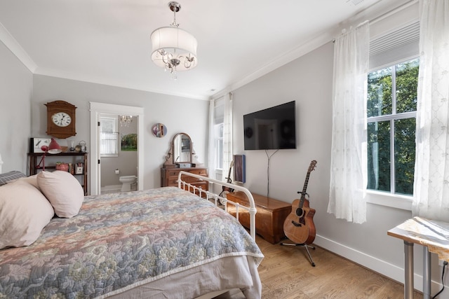 bedroom featuring ensuite bath, an inviting chandelier, light hardwood / wood-style floors, and crown molding