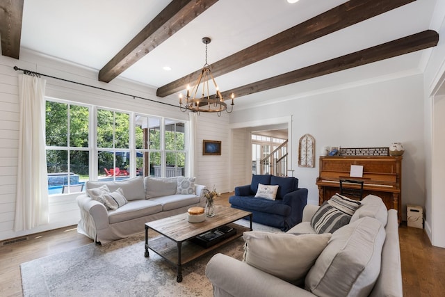 living room with beamed ceiling, hardwood / wood-style floors, and a notable chandelier