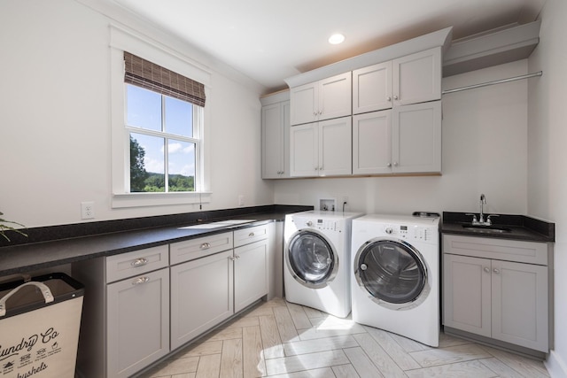 washroom with sink, cabinets, washing machine and clothes dryer, and light parquet flooring