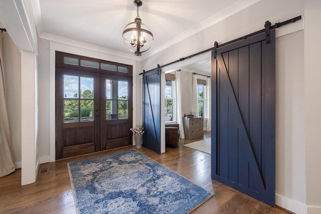 foyer with french doors, a barn door, dark hardwood / wood-style flooring, a chandelier, and crown molding