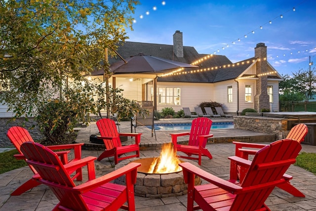 view of patio featuring a pool with hot tub, pool water feature, and a fire pit