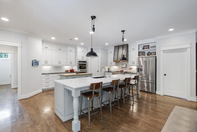 kitchen with stainless steel appliances, a large island with sink, sink, decorative light fixtures, and backsplash