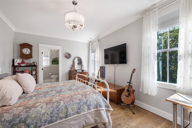 bedroom featuring ensuite bathroom, a notable chandelier, light hardwood / wood-style floors, and crown molding