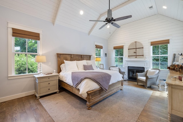 bedroom with ceiling fan, vaulted ceiling with beams, light hardwood / wood-style floors, and multiple windows