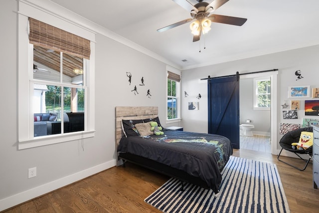 bedroom featuring hardwood / wood-style flooring, ensuite bathroom, lofted ceiling, a barn door, and ceiling fan