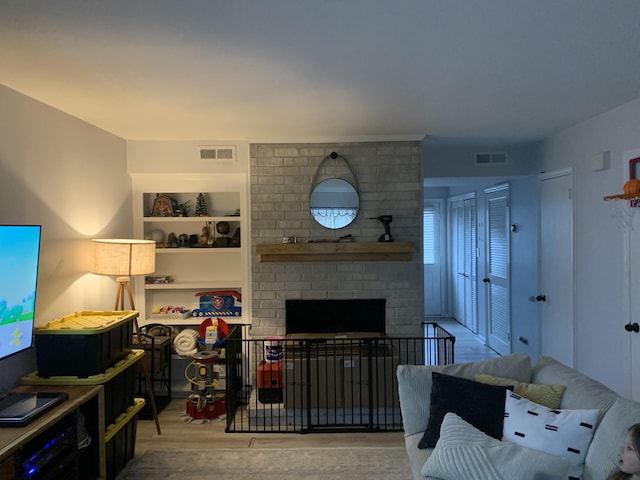 living room featuring a brick fireplace and light wood-type flooring