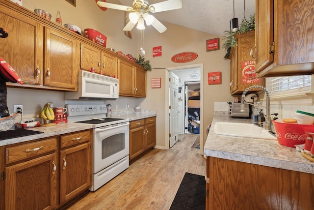 kitchen with light hardwood / wood-style floors, white appliances, lofted ceiling, hanging light fixtures, and sink