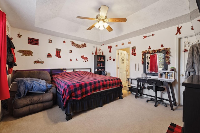 bedroom with ceiling fan, carpet, and a tray ceiling