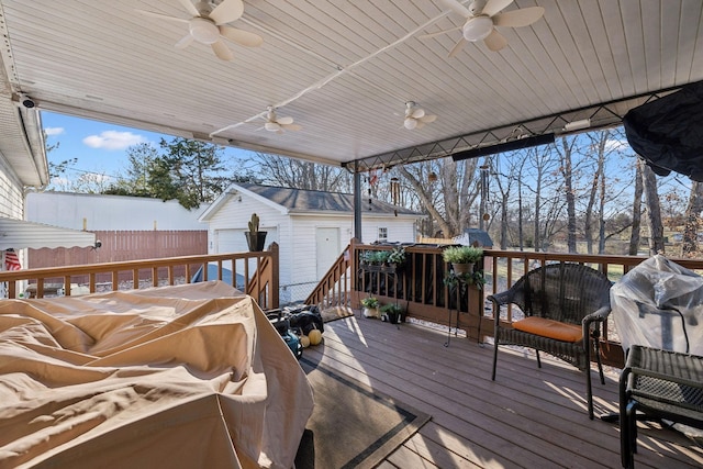 wooden deck featuring ceiling fan, a garage, and an outdoor structure