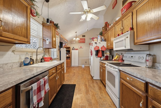 kitchen featuring pendant lighting, white appliances, a textured ceiling, lofted ceiling, and light hardwood / wood-style flooring