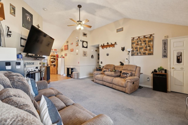 living room featuring lofted ceiling, ceiling fan, light carpet, and a textured ceiling