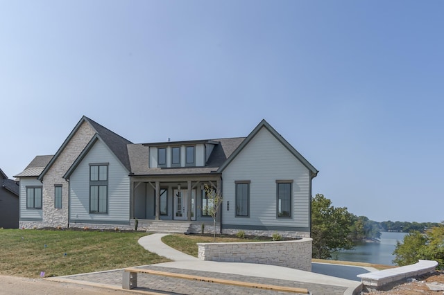 view of front of home with a front yard, covered porch, and a water view