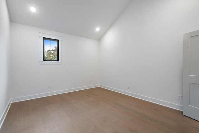 unfurnished room with dark wood-type flooring and vaulted ceiling