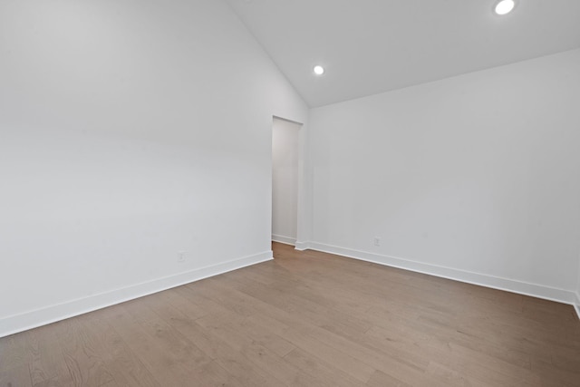 spare room featuring lofted ceiling and light wood-type flooring