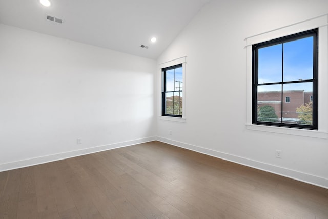 spare room with dark wood-type flooring and vaulted ceiling