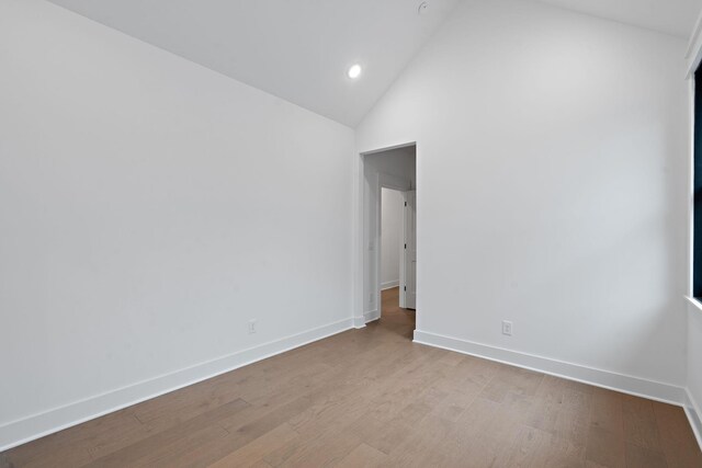 spare room featuring lofted ceiling and light hardwood / wood-style floors