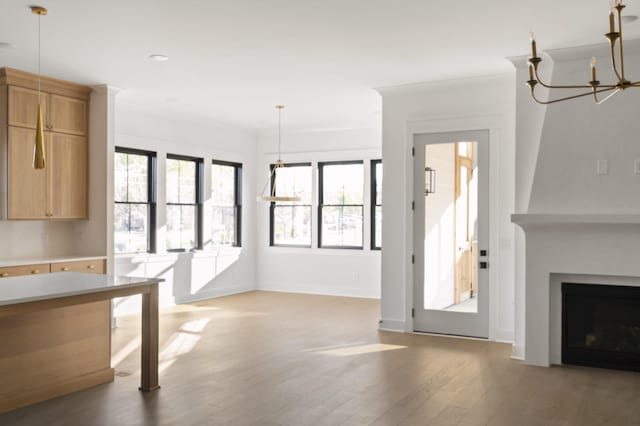 unfurnished living room featuring a chandelier, hardwood / wood-style flooring, and crown molding