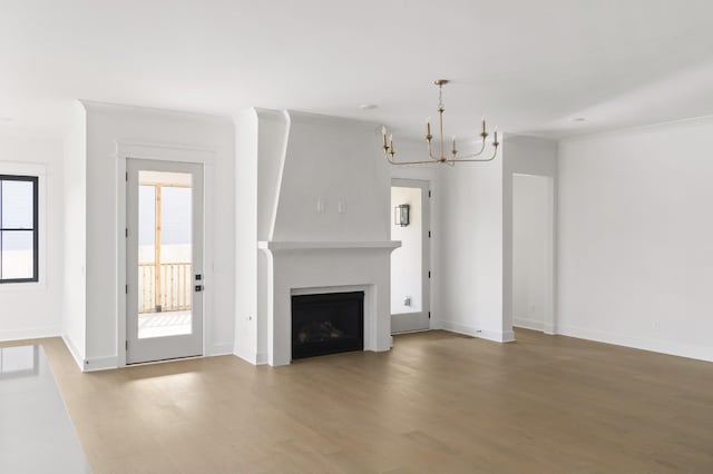 unfurnished living room featuring a notable chandelier, ornamental molding, and wood-type flooring