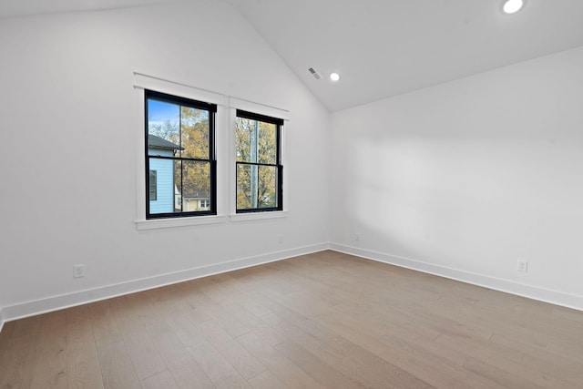 empty room with vaulted ceiling and light hardwood / wood-style flooring