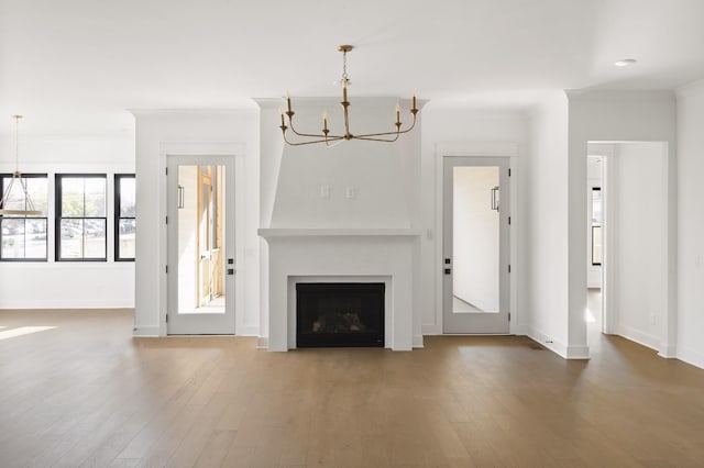 unfurnished living room featuring hardwood / wood-style floors, a chandelier, and ornamental molding