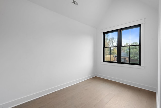 spare room with vaulted ceiling and wood-type flooring