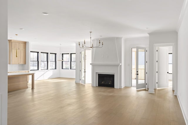 unfurnished living room featuring ornamental molding, a chandelier, and light wood-type flooring