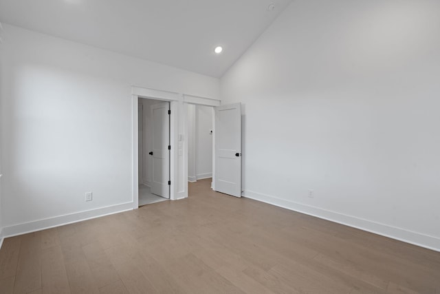 unfurnished bedroom with light hardwood / wood-style floors and lofted ceiling