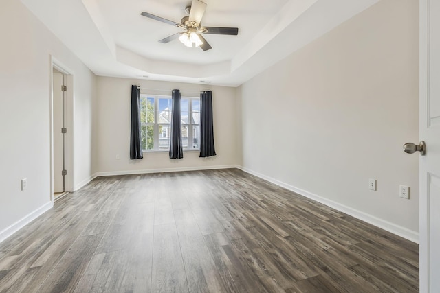 unfurnished room featuring dark hardwood / wood-style flooring, a raised ceiling, and ceiling fan