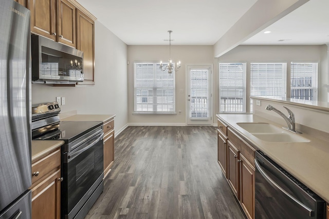 kitchen featuring an inviting chandelier, stainless steel appliances, dark wood-type flooring, sink, and decorative light fixtures